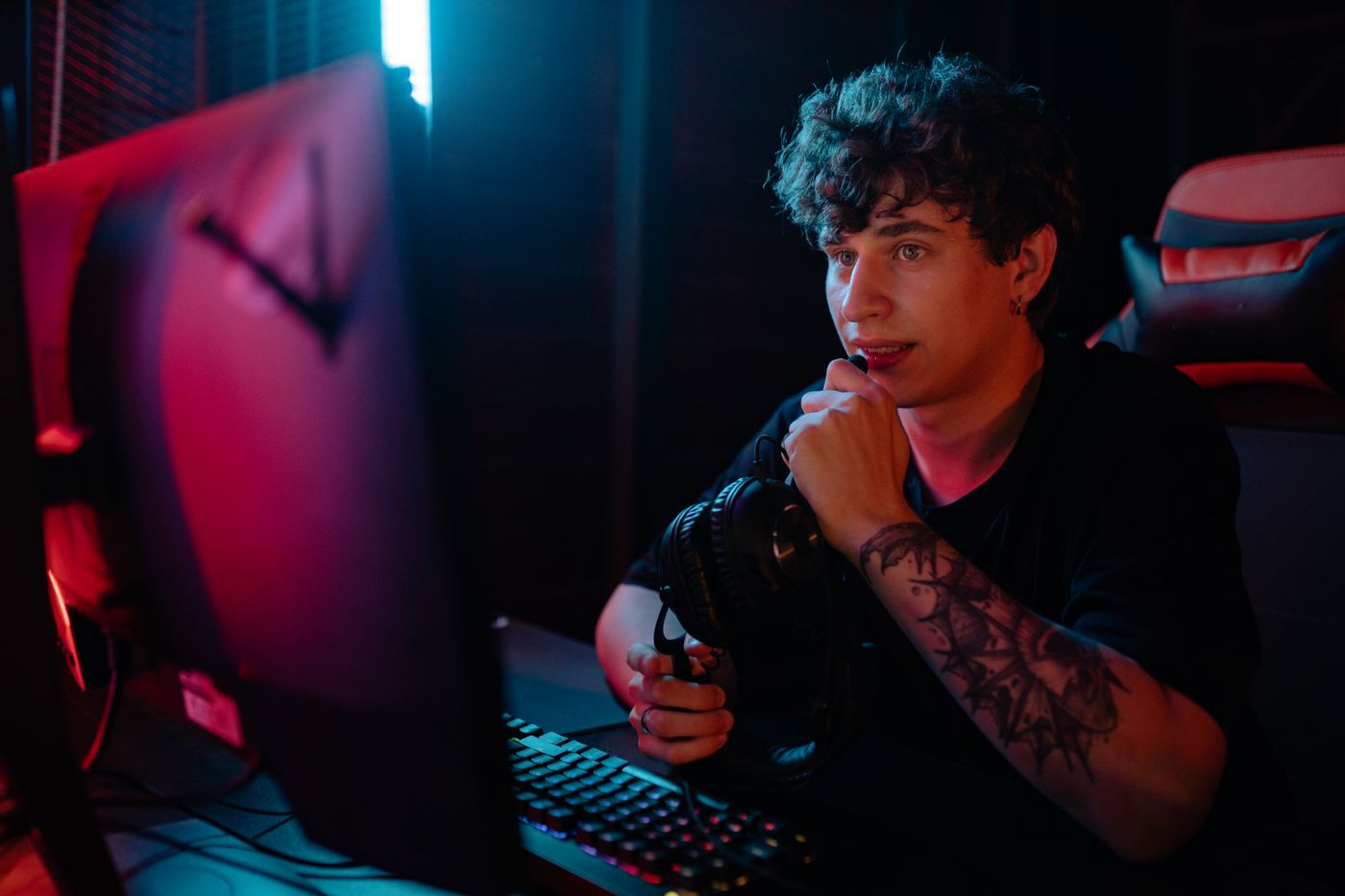 Gamer at his monitor, holding a headset microphone. Stock photograph by Yan Krukau.
